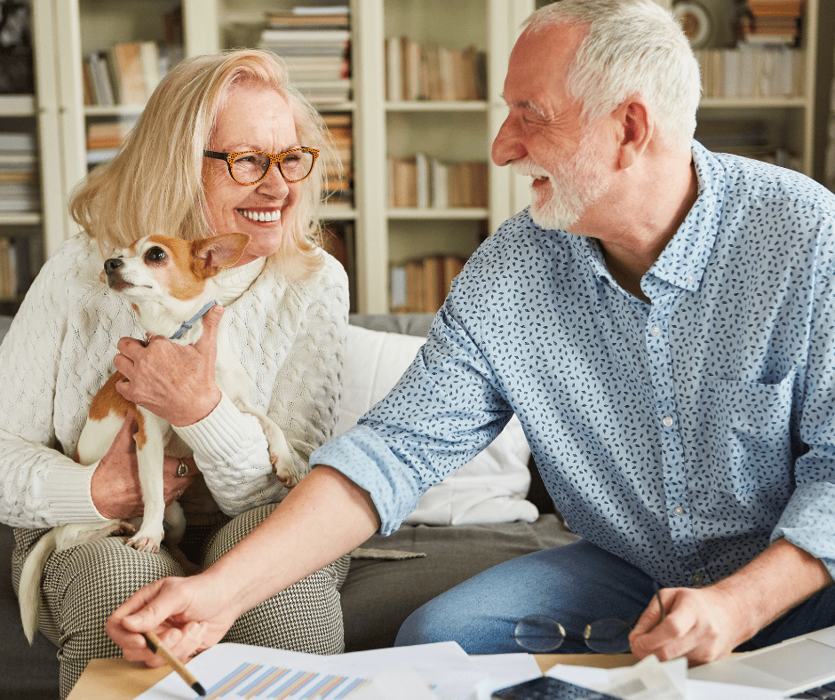 Elderly man and his wife smiling and holding small dog